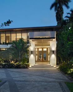 the front entrance to a modern house lit up at night