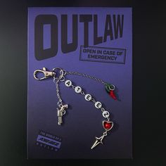 a key chain with charms attached to it on top of a purple card that says out law open in case of emergency