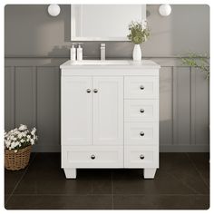 a white bathroom vanity with drawers and a mirror on the wall next to a plant