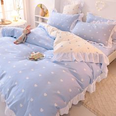 a bed with blue and white polka dot comforter, pillows and stuffed animals on it