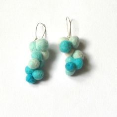 two small blue and white pom poms hanging from earrings