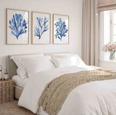 three blue and white seaweed prints on the wall above a bed in a bedroom