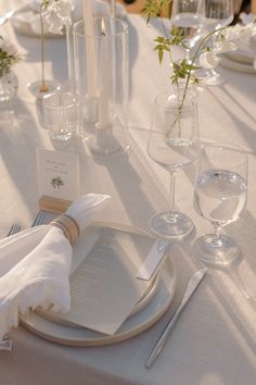 the table is set with place settings, napkins, and wine glasses for dinner