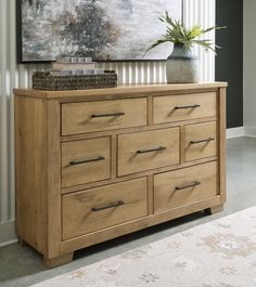 a wooden dresser with drawers and a painting on the wall behind it in a living room