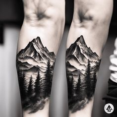 two people with tattoos on their arms are holding each other's hands and mountains