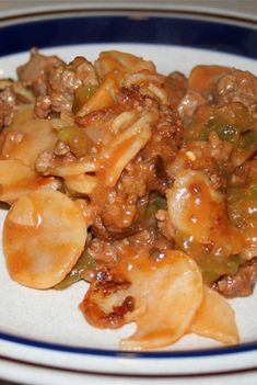 a white plate topped with pasta and meat covered in sauce on top of a table