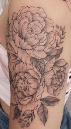 a woman's arm with flowers and leaves tattooed on the side of her body