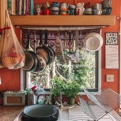 pots and pans are hanging from the ceiling in a kitchen with an open window