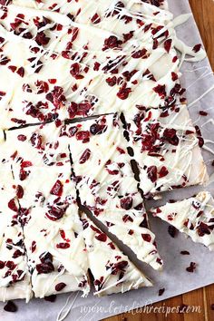 white chocolate bark with cranberries and raisins cut into squares on a piece of parchment paper