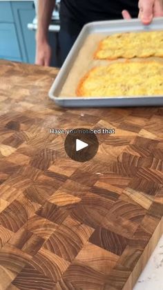 a person standing in front of a wooden cutting board with some food on top of it