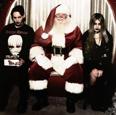 a man dressed as santa claus sitting next to two women