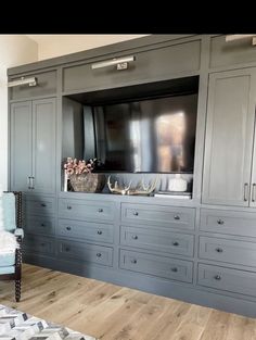 a living room with gray cabinets and a television on top of the entertainment center that is built into the wall