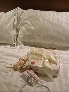 two wrapped presents sitting on top of a bed next to an unmade pillow and pillows