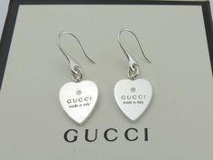 Brand: Gucci Material: 925 Sterling Silver Heart Size: Width 14 mm, Height 16 mm Hallmarks: Gucci / Made in Italy / Ag 925 Stunning square dangle earrings made by Gucci. This pair of earrings is in good condition. Some minor scratches.  They have been professionally polished. A great gift for your loved one. Gucci box (has minor signs of use) included. The earrings are hallmarked and guaranteed 100% authentic. The earrings have been authenticated by a professional before sale. 100% money back gu White Luxury Earrings For Valentine's Day, Luxury Heart-shaped Drop Earrings For Valentine's Day, Luxury Silver Heart Cut Earrings, Luxury Heart-shaped Earrings For Gifts, Luxury Heart-shaped Earrings As Gift, Luxury Heart Charm Earrings For Valentine's Day, Designer Heart-shaped Earrings As Gift, Designer Silver Jewelry With Hallmarks, Designer Heart-shaped Earrings For Gift