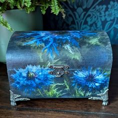 a blue painted box sitting on top of a wooden table next to a potted plant