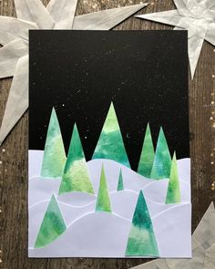 paper snowflakes and stars on a wooden surface with green trees in the background