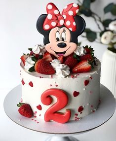 a minnie mouse birthday cake with strawberries and flowers on the top is ready to be eaten