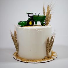 a cake with a tractor on top and wheat in the middle, sitting on a plate