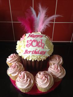 a birthday cupcake with pink frosting and feathers sits on top of a red plate