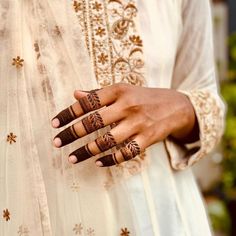 a close up of a person's hand with henna tattoos on their fingers