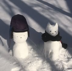 two snowmen with hats and scarves in the snow