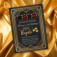 a black and gold birthday party card with red hearts on it, surrounded by golden fabric