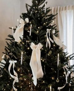 a decorated christmas tree with white ribbons and lights