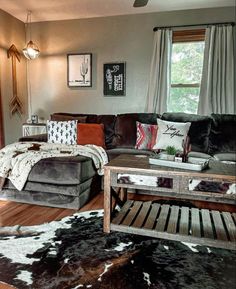 a living room filled with furniture and a cowhide rug on top of a hard wood floor