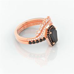 a rose gold ring with black and white stones on the sides, set against a plain background