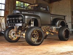 a black truck with gold rims parked in a garage