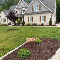 a house with a for sale sign in front of it and landscaping around the yard