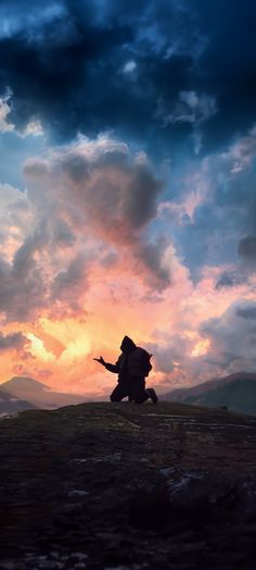 a man kneeling on top of a hill under a cloudy sky