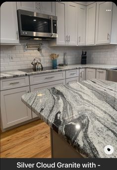 a kitchen with marble counter tops and white cabinets