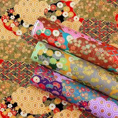 four rolls of colorful fabric sitting next to each other on top of a cloth covered floor