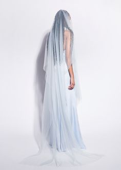 the back of a woman wearing a blue veil and dress with sheer fabric on it