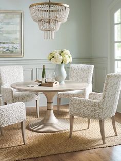 a dining room table with chairs and a chandelier hanging from the ceiling above it