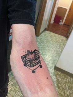 a person with a small tattoo on their arm that has an image of a cat in a basket