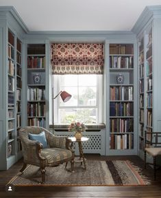 a living room filled with furniture and bookshelves next to a window covered in curtains