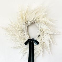 a white wreath with black ribbon hanging on the wall