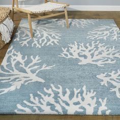 a blue and white rug with corals on it in a living room next to a chair