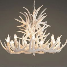 a chandelier made out of antlers with candles in the center and one light on each side