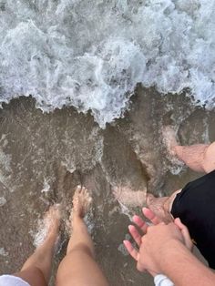 two people standing on the beach with their feet in the water