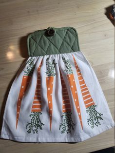 an orange and white dress with carrots on the front is sitting on a table