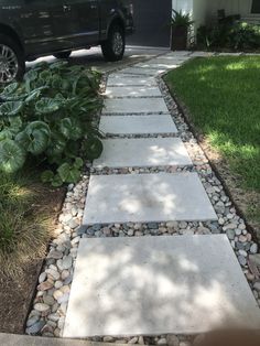 a black truck parked in front of a house next to a stone path that is lined with plants