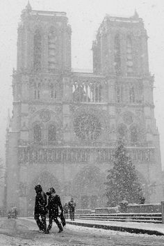 two people walking in the snow near a cathedral