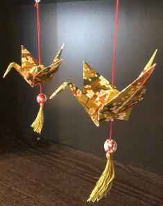 two origami cranes hanging from red string