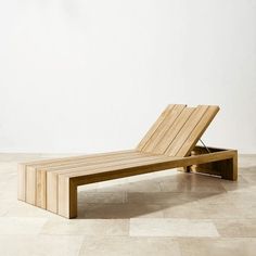 a wooden chaise lounger sitting on top of a tile floor next to a white wall