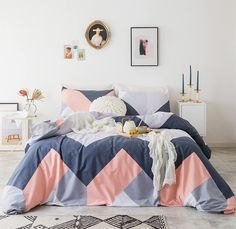 a bedroom with a bed covered in blue and pink comforters, pillows and pictures on the wall