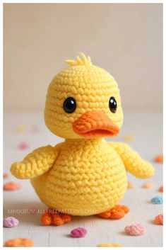 a crocheted yellow duck sitting on top of confetti sprinkles