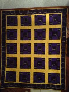 a purple and yellow quilt hanging on a wall